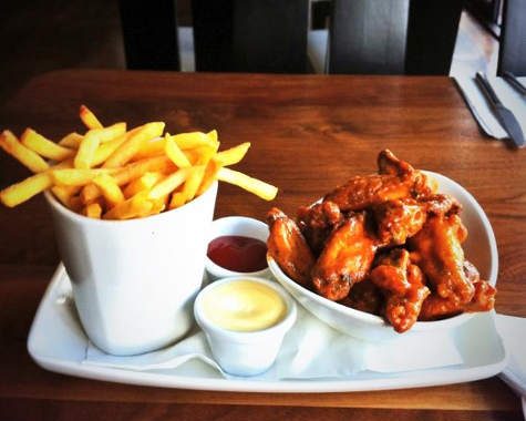Spicy chicken wings with fries and sauces